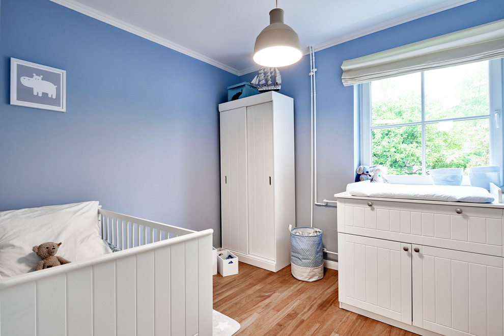 Esempio di una cameretta per neonato minimal di medie dimensioni con pareti blu, pavimento in legno massello medio e pavimento marrone