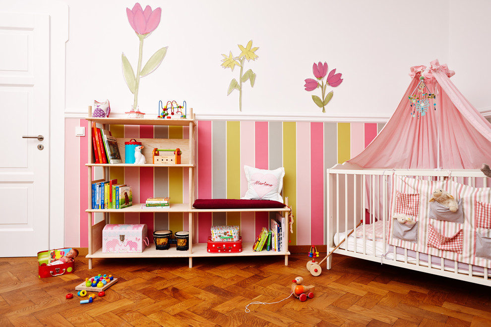 Diseño de habitación de bebé niña clásica con paredes blancas, suelo de madera clara y suelo naranja