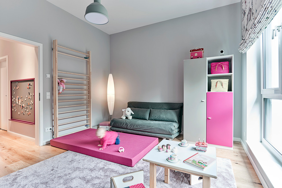 Inspiration pour une chambre de bébé fille design de taille moyenne avec un mur gris, un sol en bois brun et un sol marron.