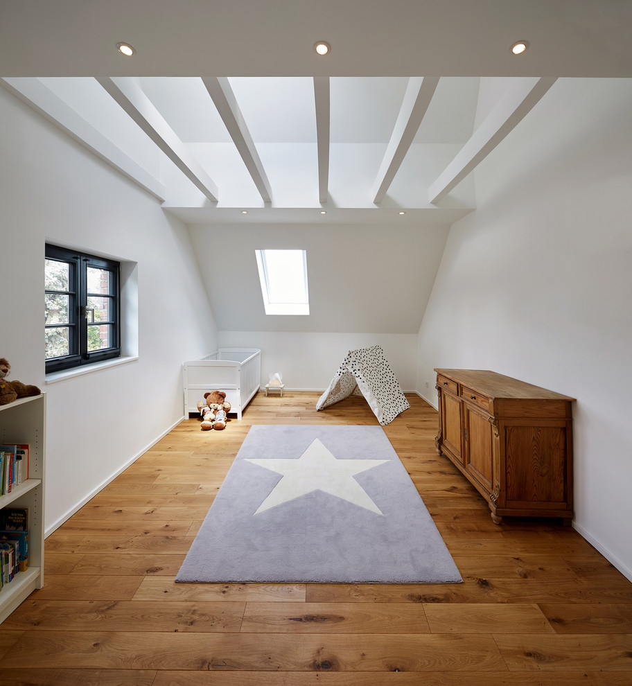 Medium sized farmhouse gender neutral nursery in Cologne with white walls, medium hardwood flooring and brown floors.