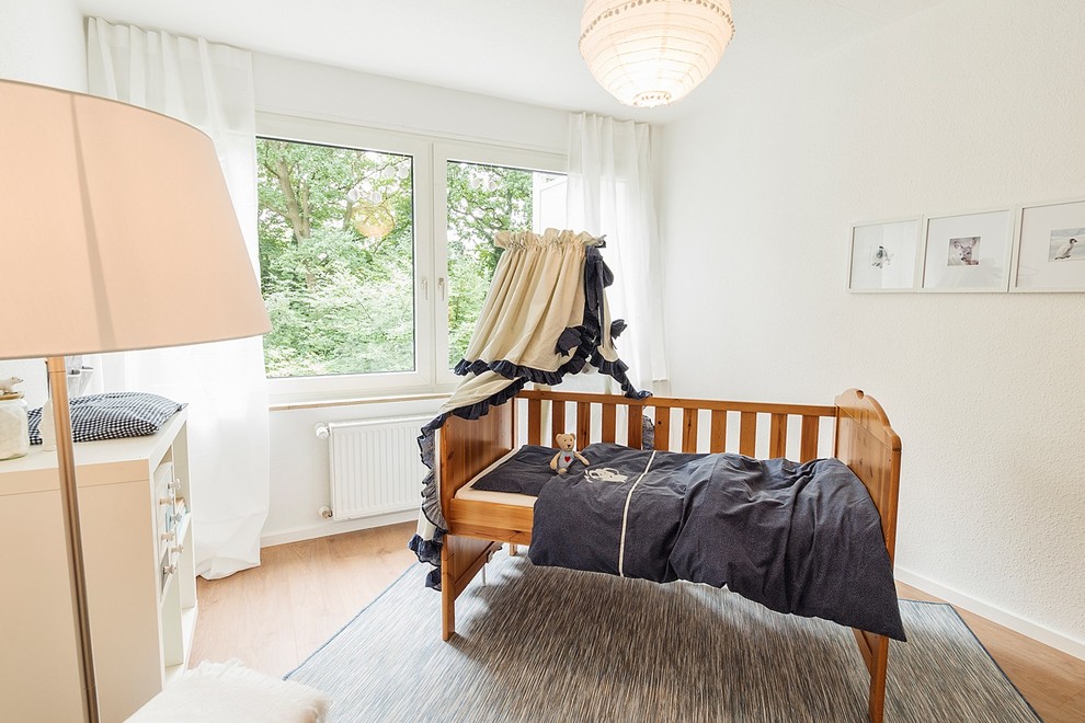 Inspiration pour une petite chambre de bébé neutre nordique avec un mur blanc, parquet clair et un sol marron.