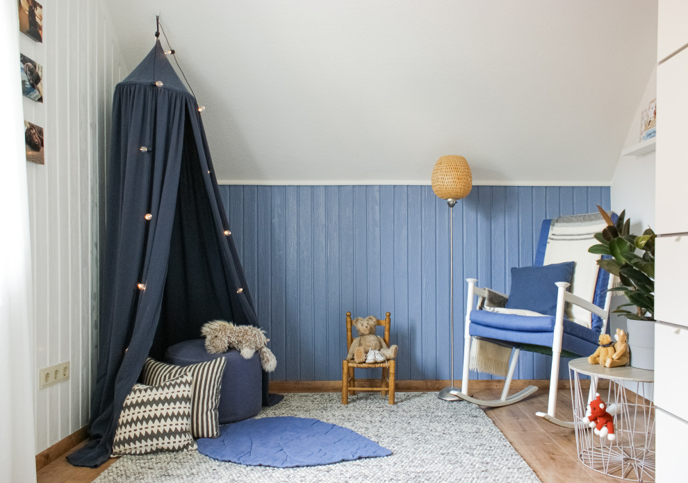 Exemple d'une chambre de bébé garçon nature de taille moyenne avec un mur bleu, sol en stratifié et un sol marron.