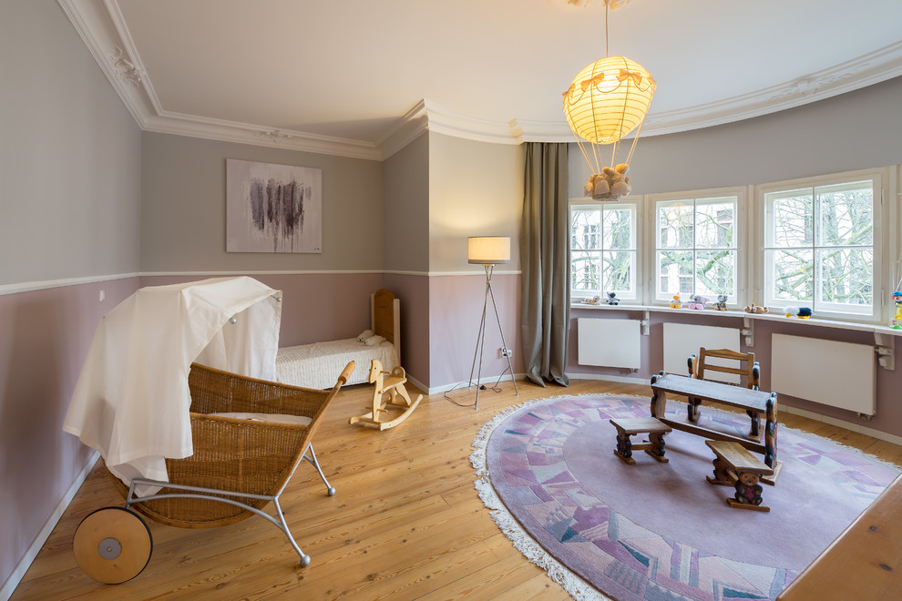 Modelo de habitación de bebé neutra clásica con paredes multicolor, suelo de madera en tonos medios y suelo marrón