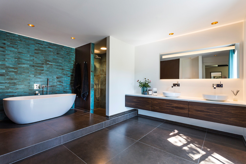 Design ideas for a contemporary ensuite bathroom in Copenhagen with flat-panel cabinets, dark wood cabinets, a freestanding bath, a corner shower, blue tiles, white walls, a vessel sink, solid surface worktops and an open shower.