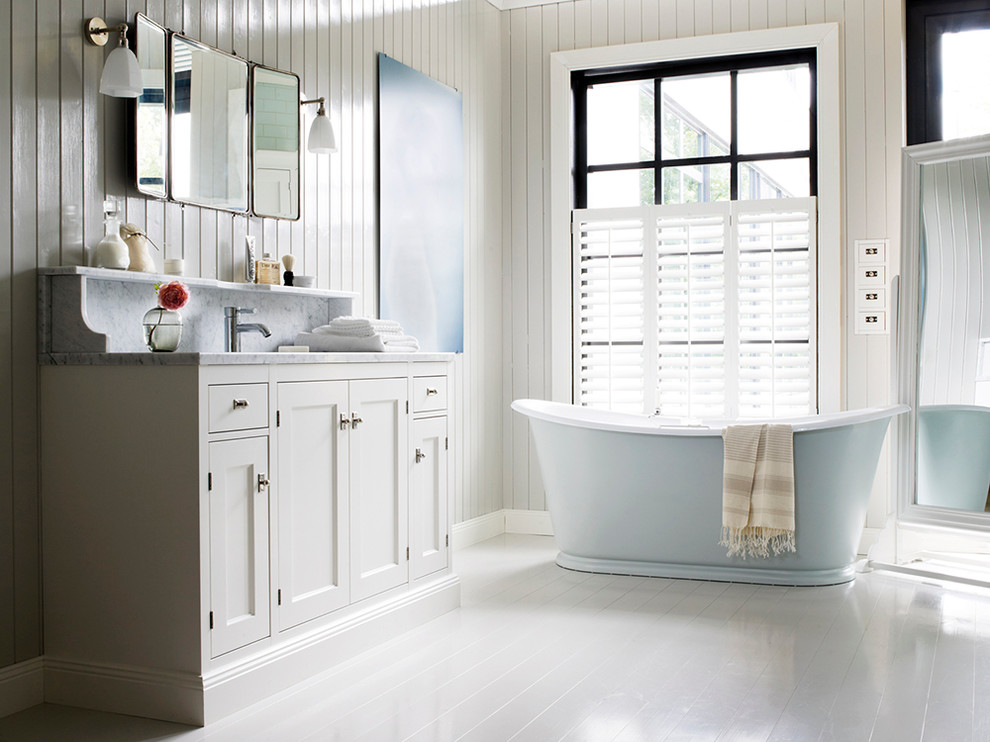 Immagine di una stanza da bagno nordica con ante con riquadro incassato, ante bianche e vasca freestanding