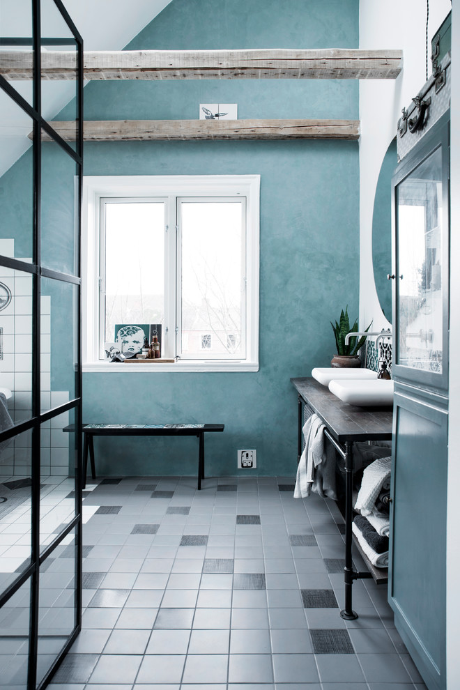 Ejemplo de cuarto de baño industrial con aseo y ducha y paredes azules