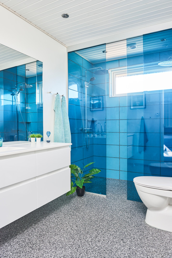 Mittelgroßes Modernes Badezimmer En Suite mit grauen Schränken, blauen Fliesen, Schiebetür-Duschabtrennung, flächenbündigen Schrankfronten, weißer Wandfarbe und grauem Boden in Odense