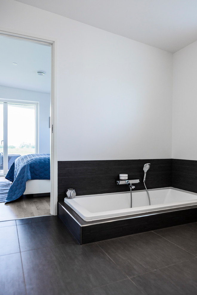 Idée de décoration pour une salle de bain nordique avec une baignoire posée et un sol noir.