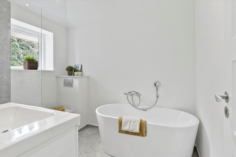 コペンハーゲンにある小さな北欧スタイルのおしゃれなマスターバスルーム (置き型浴槽、シャワー付き浴槽	、白いキャビネット、グレーのタイル、白い壁、コンソール型シンク、グレーの床、オープンシャワー) の写真