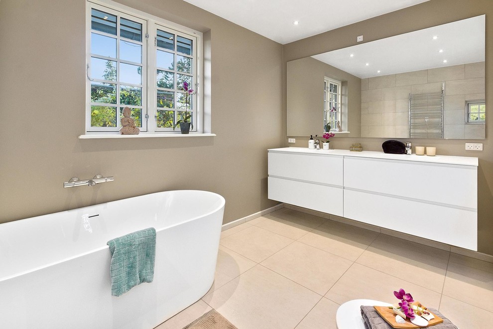На фото: большая ванная комната в стиле модернизм с плоскими фасадами, белыми фасадами, отдельно стоящей ванной, коричневыми стенами, бежевым полом и белой столешницей
