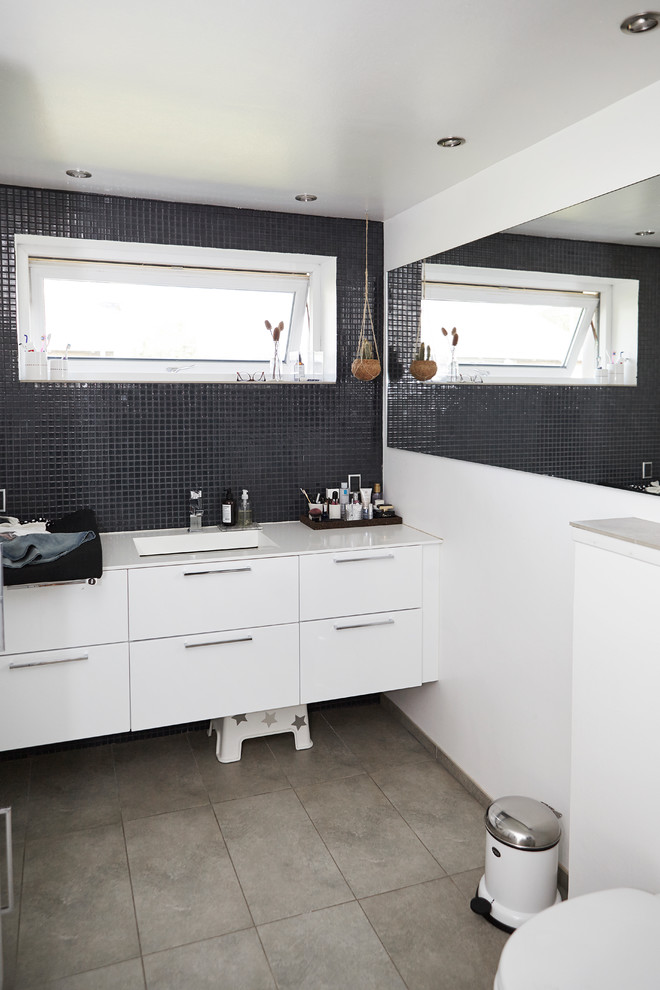 На фото: ванная комната в скандинавском стиле с черными стенами, врезной раковиной и серым полом
