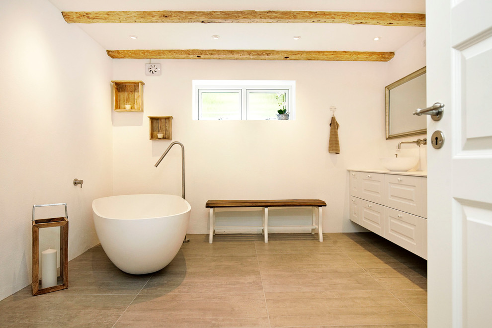 Großes Skandinavisches Badezimmer En Suite mit profilierten Schrankfronten, weißen Schränken, freistehender Badewanne, weißer Wandfarbe, Aufsatzwaschbecken und Keramikboden in Kopenhagen