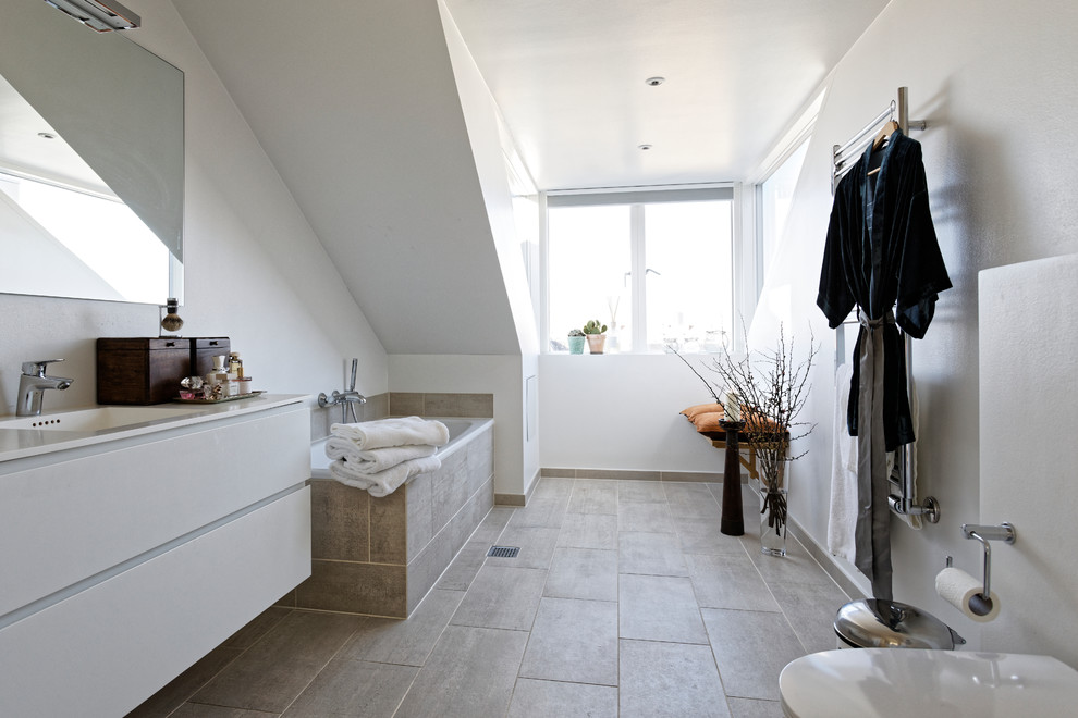 Inspiration för skandinaviska vitt badrum, med släta luckor, vita skåp, en vägghängd toalettstol, vita väggar, ett integrerad handfat och beiget golv