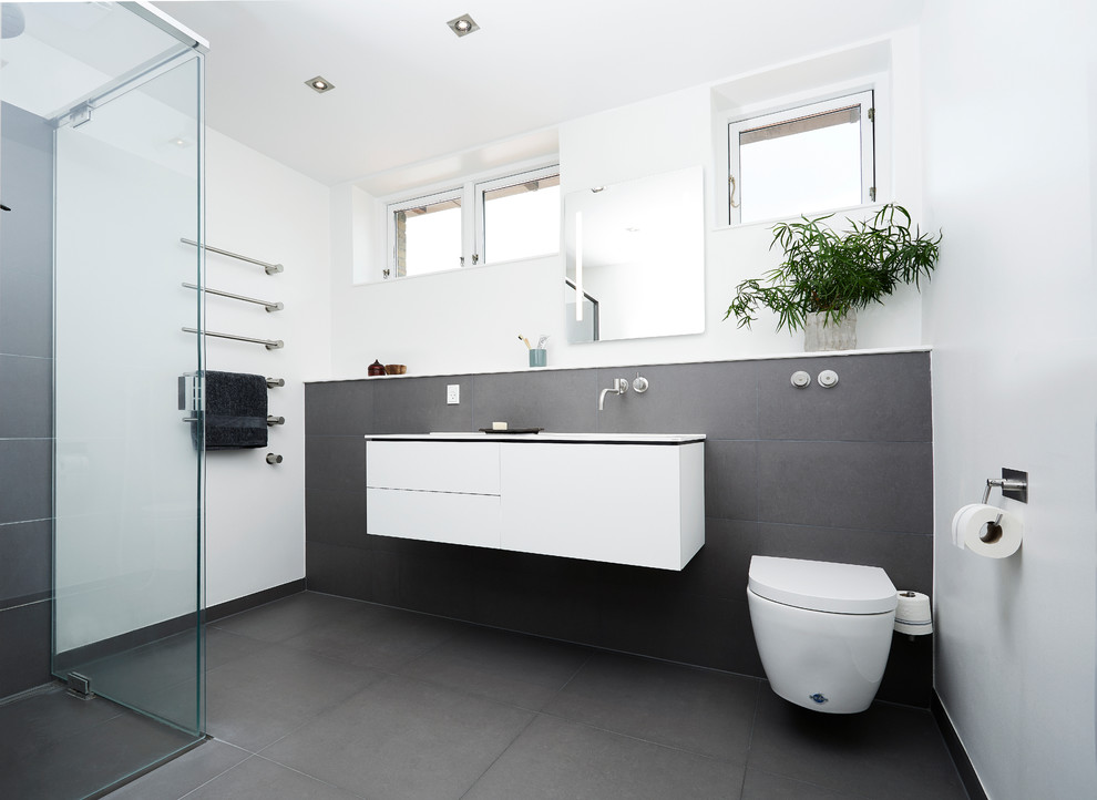 Idee per una stanza da bagno nordica di medie dimensioni con ante lisce, ante bianche, WC sospeso, lavabo sospeso e pavimento grigio