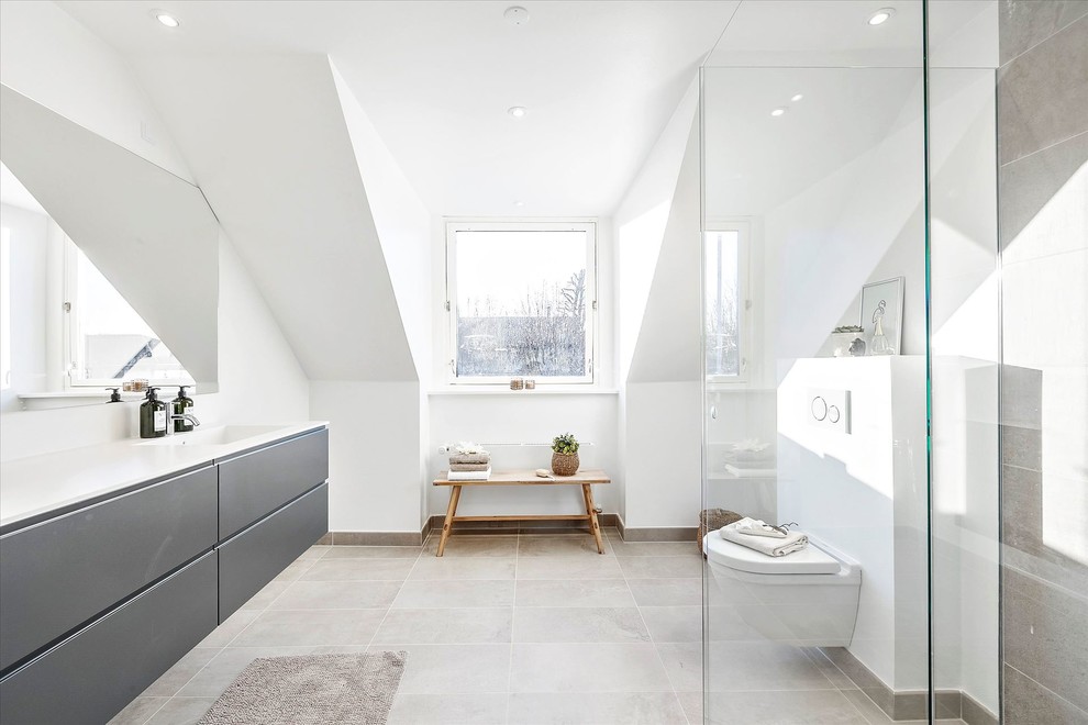 Modernes Badezimmer mit flächenbündigen Schrankfronten, grauen Schränken, Wandtoilette, grauen Fliesen, weißer Wandfarbe, grauem Boden und weißer Waschtischplatte in Kopenhagen