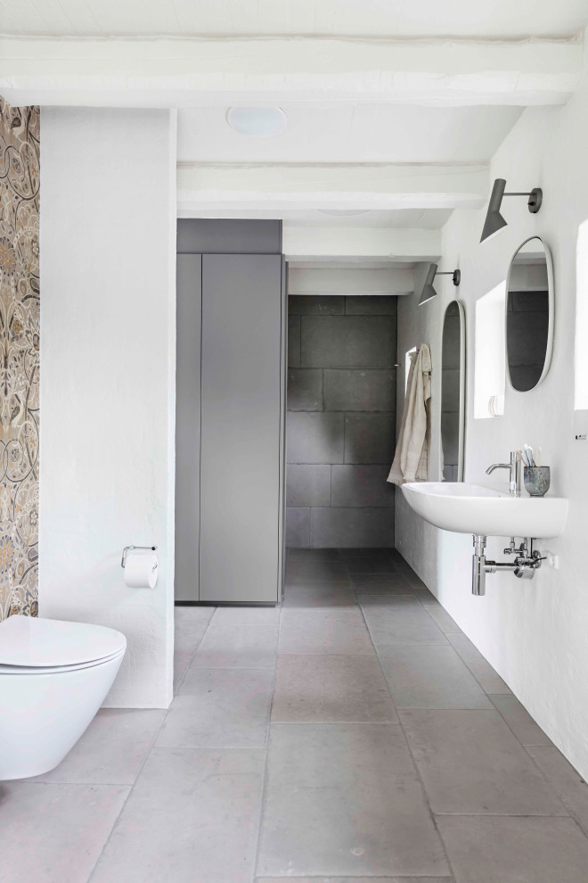На фото: ванная комната в скандинавском стиле с инсталляцией, полом из известняка, подвесной раковиной, серым полом, тумбой под одну раковину и балками на потолке