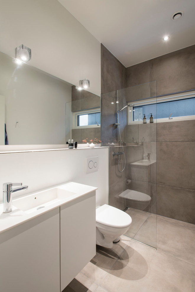 Exempel på ett mellanstort skandinaviskt badrum, med släta luckor, vita skåp, en hörndusch, en vägghängd toalettstol, grå kakel, flerfärgade väggar och grått golv