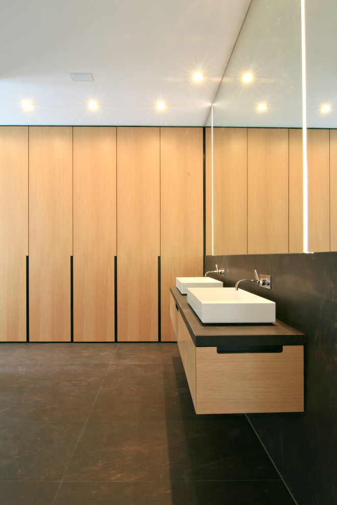Foto på ett mellanstort funkis badrum, med ett fristående handfat, släta luckor, skåp i ljust trä, brun kakel, bänkskiva i kalksten och kalkstensgolv