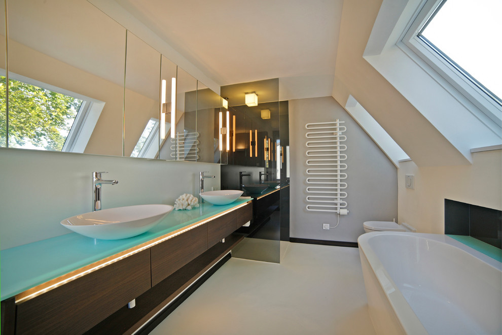 Idée de décoration pour une salle de bain principale design en bois foncé de taille moyenne avec une vasque, un placard à porte plane, un plan de toilette en surface solide, une baignoire indépendante, une douche à l'italienne, WC suspendus et un mur blanc.