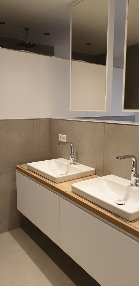 This is an example of a small modern shower room bathroom in Other with flat-panel cabinets, white cabinets, a built-in bath, grey tiles, stone tiles, grey walls, a vessel sink, solid surface worktops, grey floors, brown worktops, double sinks and a floating vanity unit.