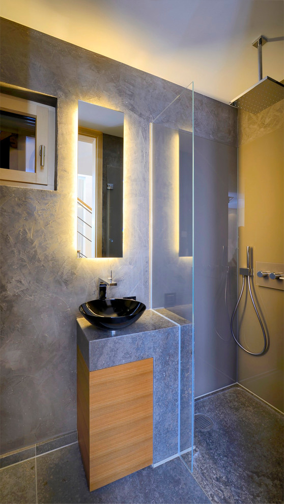 Idéer för små funkis badrum med dusch, med ett fristående handfat, släta luckor, skåp i mellenmörkt trä, granitbänkskiva, en kantlös dusch, grå kakel, grå väggar och skiffergolv