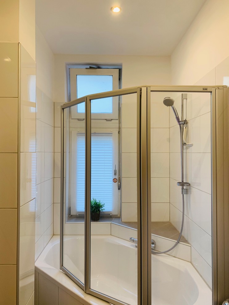 Idéer för mellanstora funkis vitt badrum med dusch, med vita skåp, ett hörnbadkar, en dusch/badkar-kombination, en vägghängd toalettstol, vit kakel, keramikplattor, vita väggar, klinkergolv i keramik, ett väggmonterat handfat, bänkskiva i akrylsten, grått golv och dusch med gångjärnsdörr