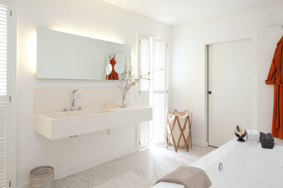 На фото: ванная комната среднего размера в современном стиле с монолитной раковиной, белой плиткой, плиткой мозаикой, полом из мозаичной плитки, белыми стенами и зеркалом с подсветкой