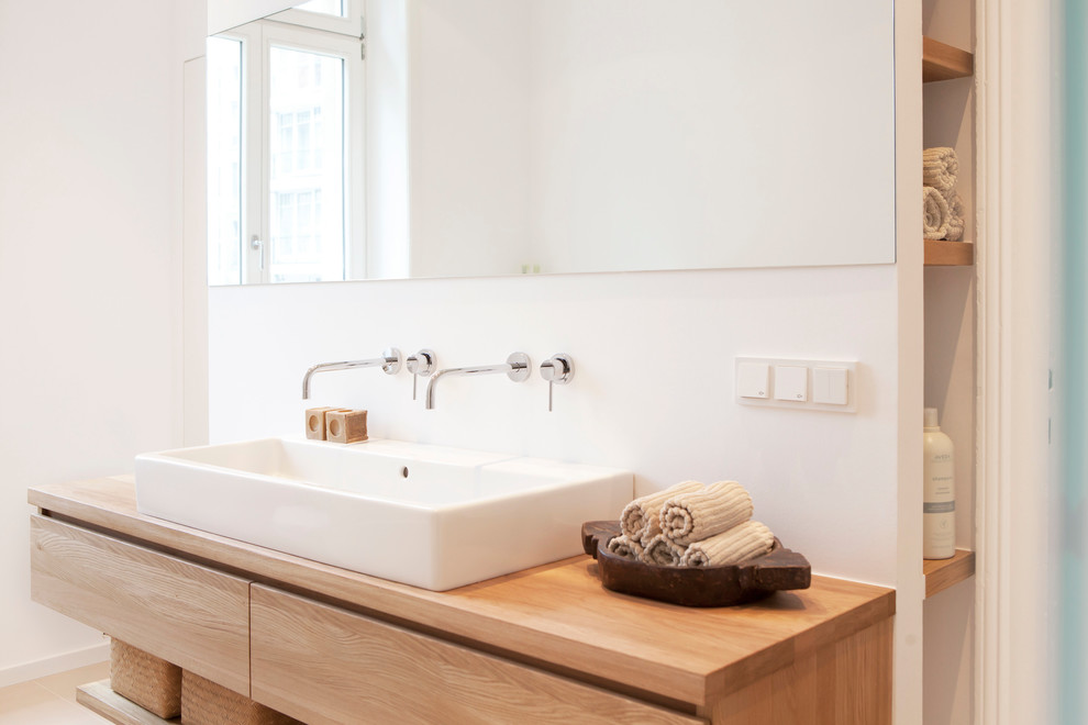 Contemporary bathroom in Frankfurt with flat-panel cabinets, light wood cabinets, beige tiles, white walls, a vessel sink and wooden worktops.
