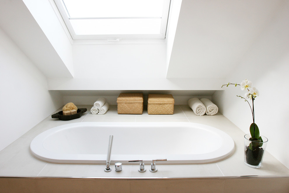 Aménagement d'une salle de bain contemporaine avec une baignoire posée et un mur blanc.