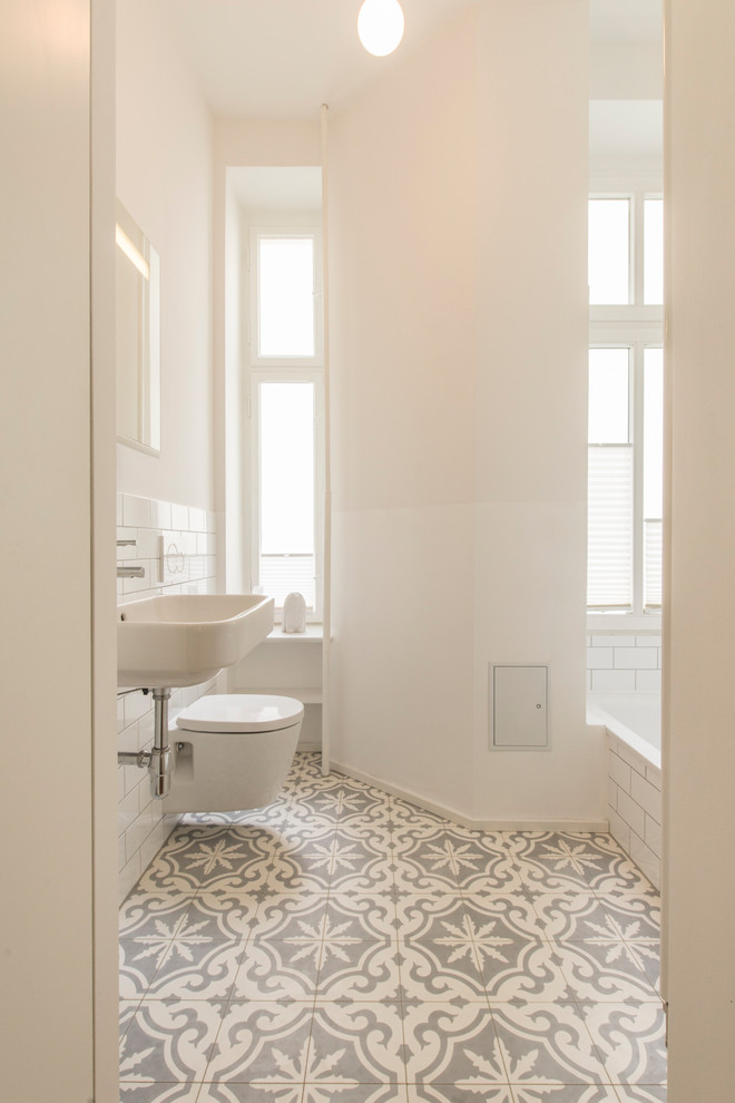 Kleines Modernes Duschbad mit Einbaubadewanne, Wandtoilette mit Spülkasten, weißen Fliesen, Metrofliesen, weißer Wandfarbe, Keramikboden, Wandwaschbecken und beigem Boden in Berlin