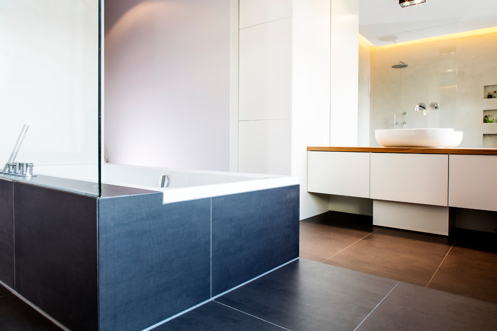 Design ideas for a medium sized contemporary bathroom in Munich with open cabinets, a built-in bath, a built-in shower, a wall mounted toilet, grey tiles, ceramic tiles, grey walls, medium hardwood flooring, a console sink, solid surface worktops, brown floors and an open shower.