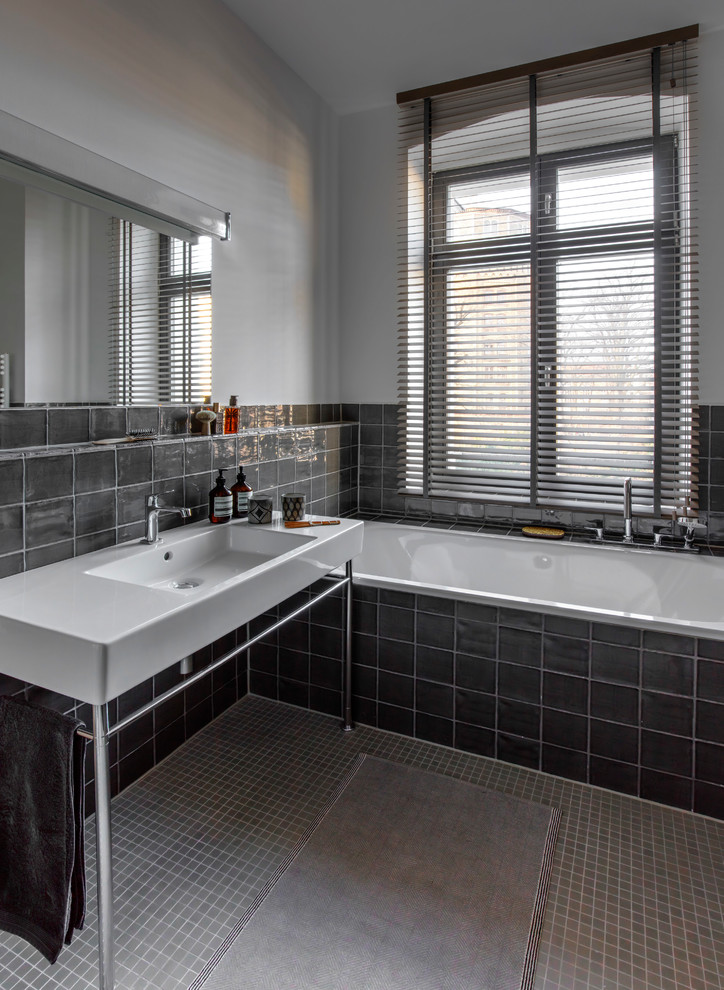 Mittelgroßes Modernes Badezimmer mit Einbaubadewanne, schwarzen Fliesen, Keramikfliesen, weißer Wandfarbe, Keramikboden, grauem Boden und Waschtischkonsole in Berlin