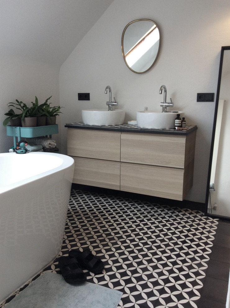 Medium sized modern ensuite bathroom in Dusseldorf with beaded cabinets, brown cabinets, a freestanding bath, an alcove shower, a two-piece toilet, white tiles, marble tiles, white walls, ceramic flooring, a vessel sink, tiled worktops, black floors, a sliding door and black worktops.