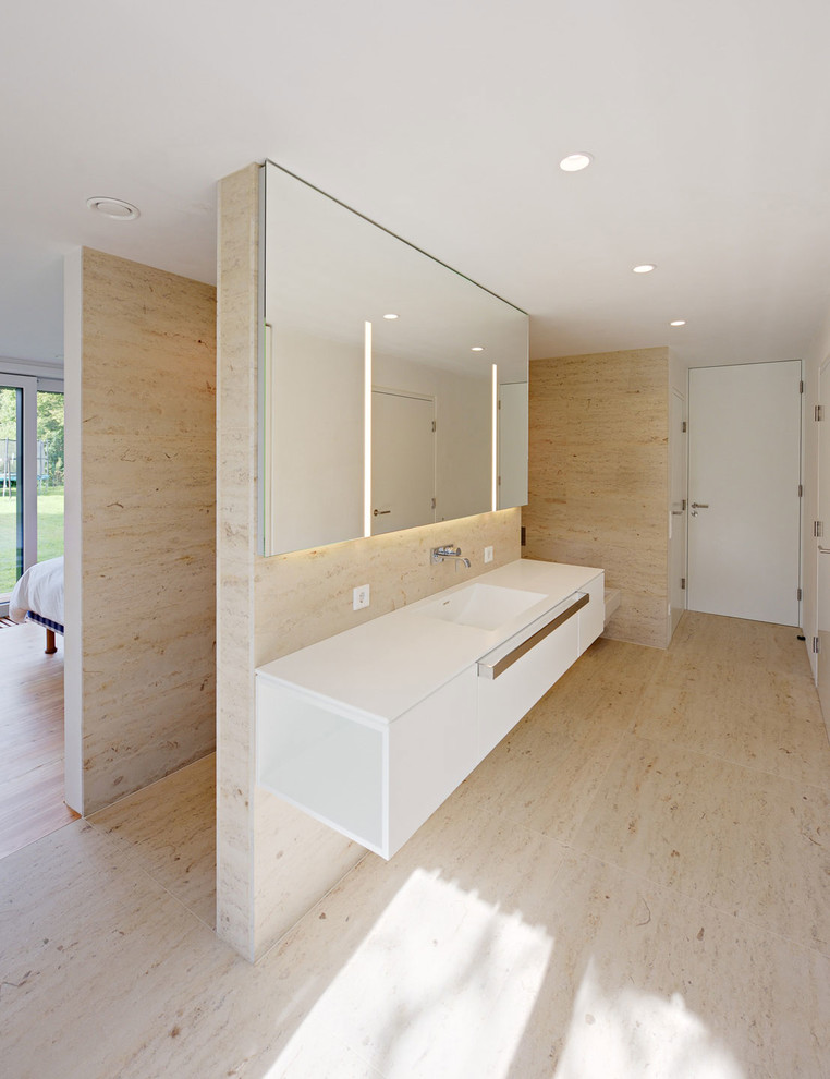 Idee per una grande stanza da bagno minimal con ante lisce, ante bianche, piastrelle beige, lastra di pietra, pavimento in pietra calcarea e lavabo integrato