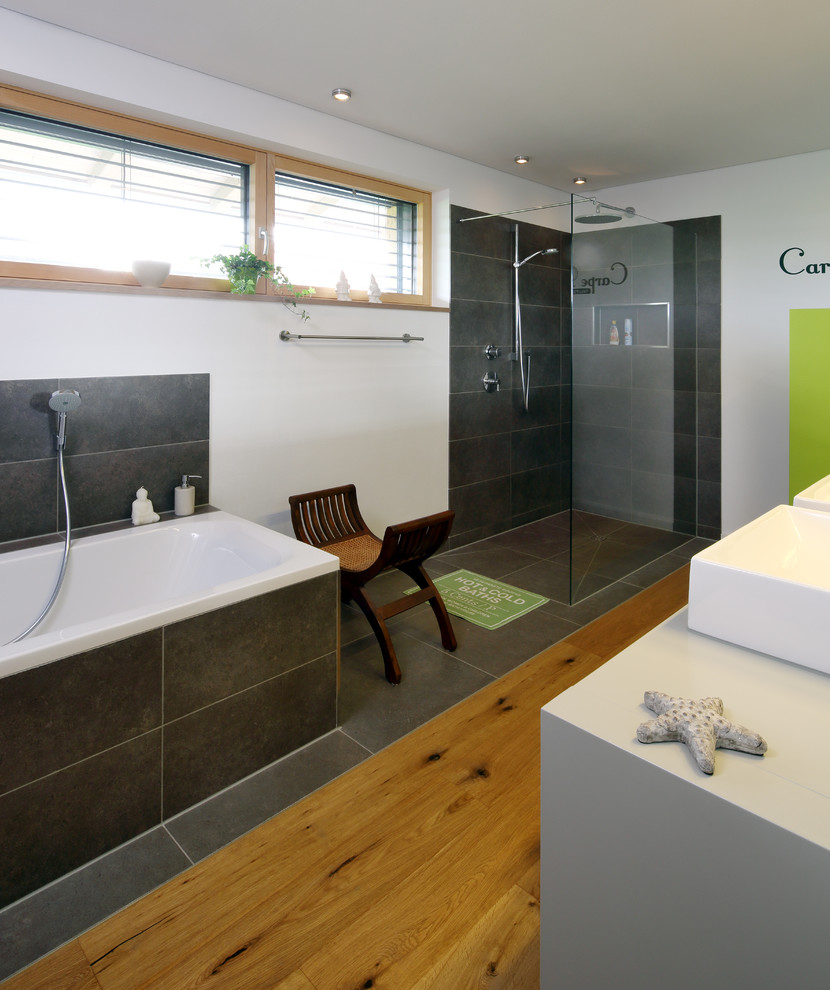 Exemple d'une salle d'eau tendance de taille moyenne avec un espace douche bain, un carrelage gris, une baignoire posée, des carreaux de béton, un mur blanc, une vasque, aucune cabine et un plan de toilette blanc.
