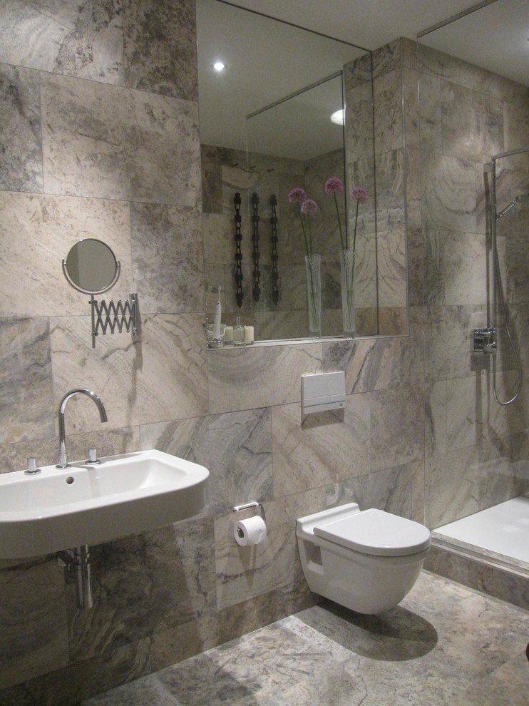 This is an example of a small contemporary bathroom in Berlin with a wall-mounted sink, a wall mounted toilet, grey tiles, stone tiles, grey walls, travertine flooring and a corner shower.