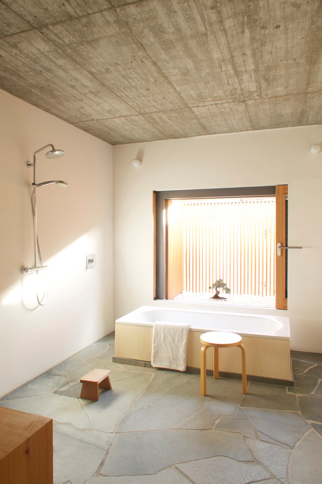 Ispirazione per una stanza da bagno con doccia etnica di medie dimensioni con vasca freestanding, doccia aperta, pareti bianche, pavimento grigio e doccia aperta
