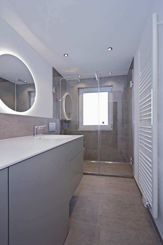 Foto di una piccola stanza da bagno con doccia minimal con ante lisce, ante grigie, WC sospeso, piastrelle grigie, piastrelle di cemento, pareti bianche, top in superficie solida, pavimento grigio e top bianco