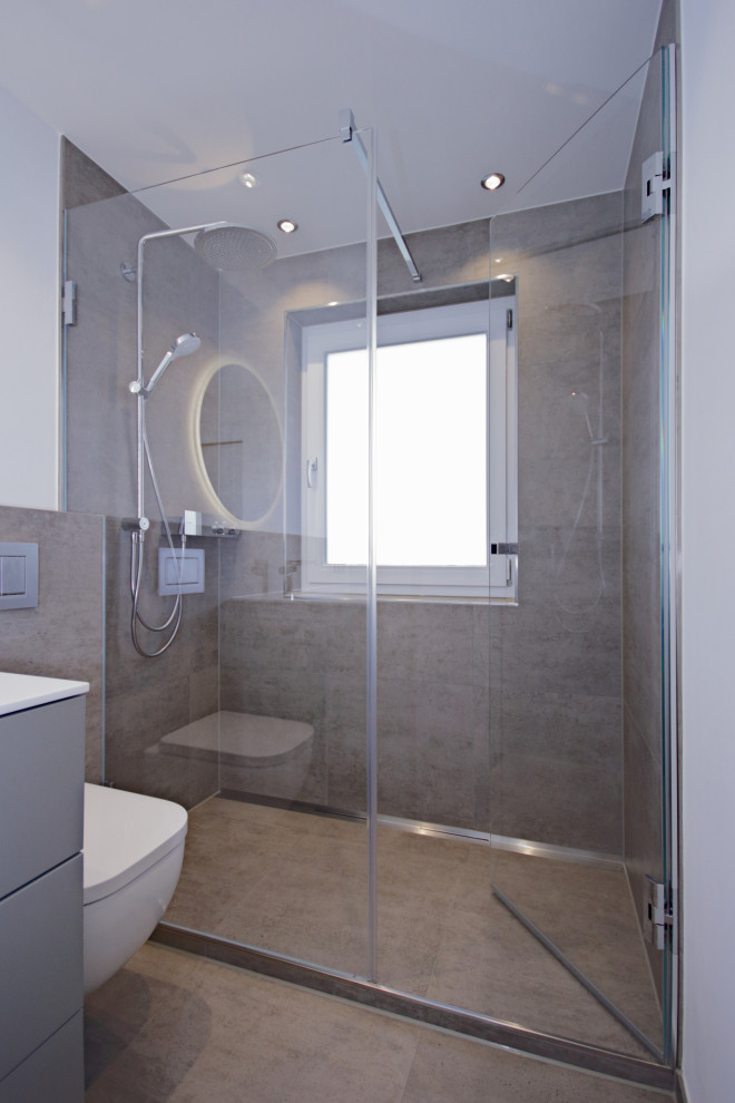 Kleines Modernes Duschbad mit flächenbündigen Schrankfronten, grauen Schränken, Wandtoilette, grauen Fliesen, Zementfliesen, weißer Wandfarbe, Mineralwerkstoff-Waschtisch, grauem Boden und weißer Waschtischplatte in München