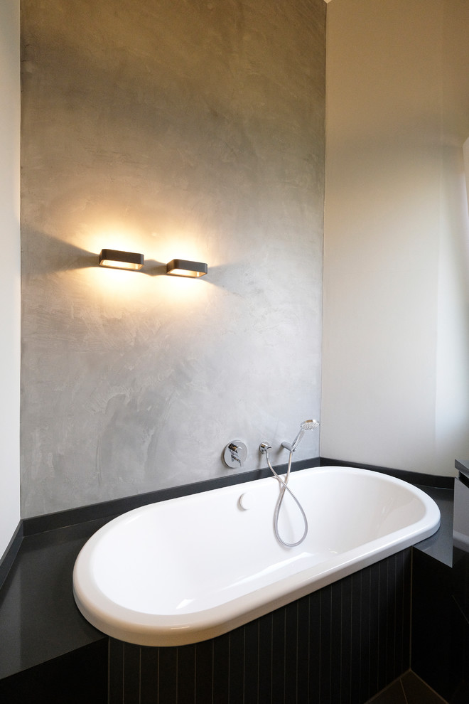 Modernes Badezimmer mit Einbaubadewanne, grauer Wandfarbe und Kalkstein in Dortmund