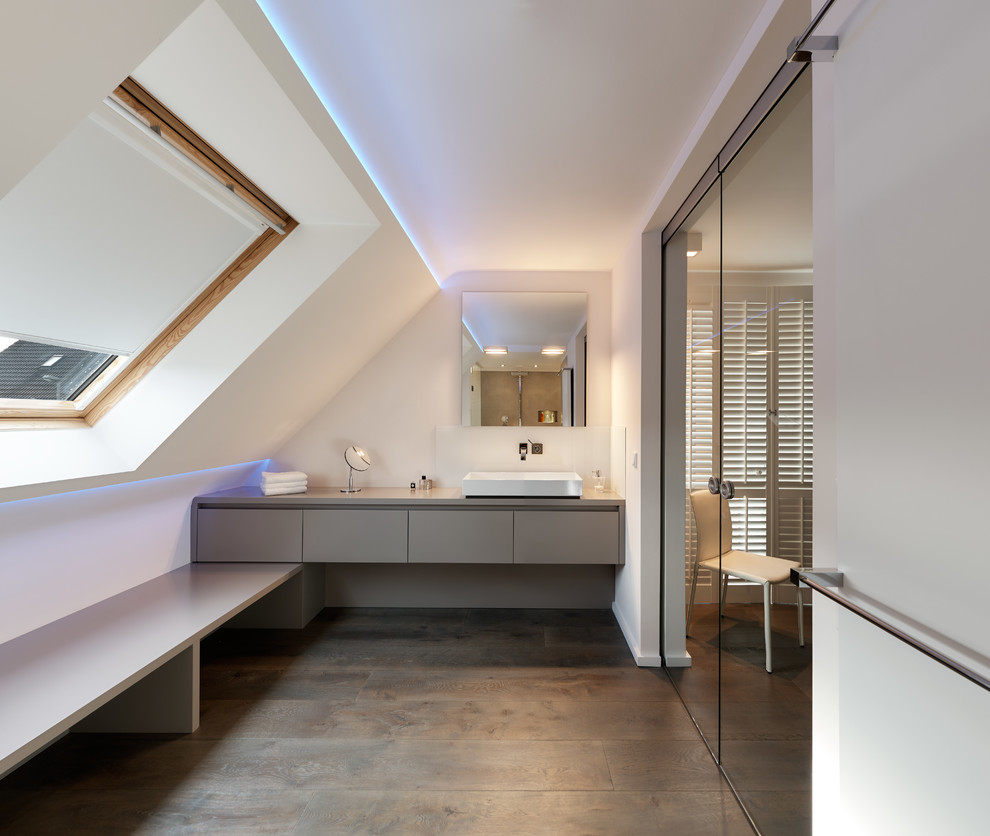 Cette photo montre une salle de bain tendance de taille moyenne avec un placard à porte plane, des portes de placard grises, un mur blanc, parquet foncé et une vasque.