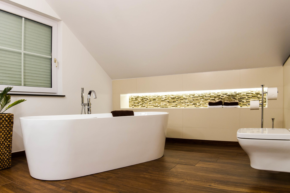 Foto på ett stort funkis en-suite badrum, med öppna hyllor, ett fristående badkar, en vägghängd toalettstol, flerfärgad kakel, mosaik, vita väggar och mörkt trägolv