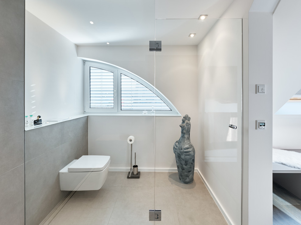 Esempio di una stanza da bagno design con WC sospeso, piastrelle beige e lastra di pietra
