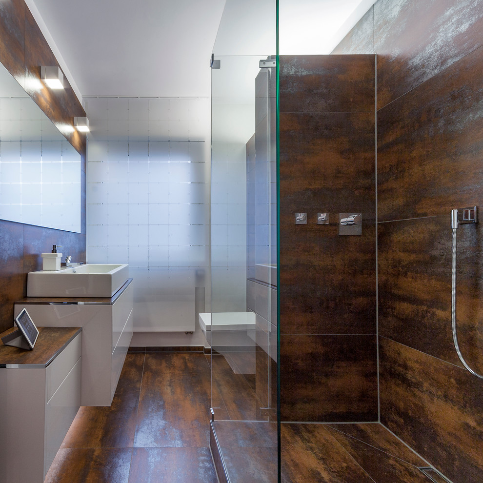 Aménagement d'une petite salle d'eau contemporaine avec une vasque, un placard à porte plane, des portes de placard blanches, un carrelage marron, un mur blanc, une douche à l'italienne et WC suspendus.