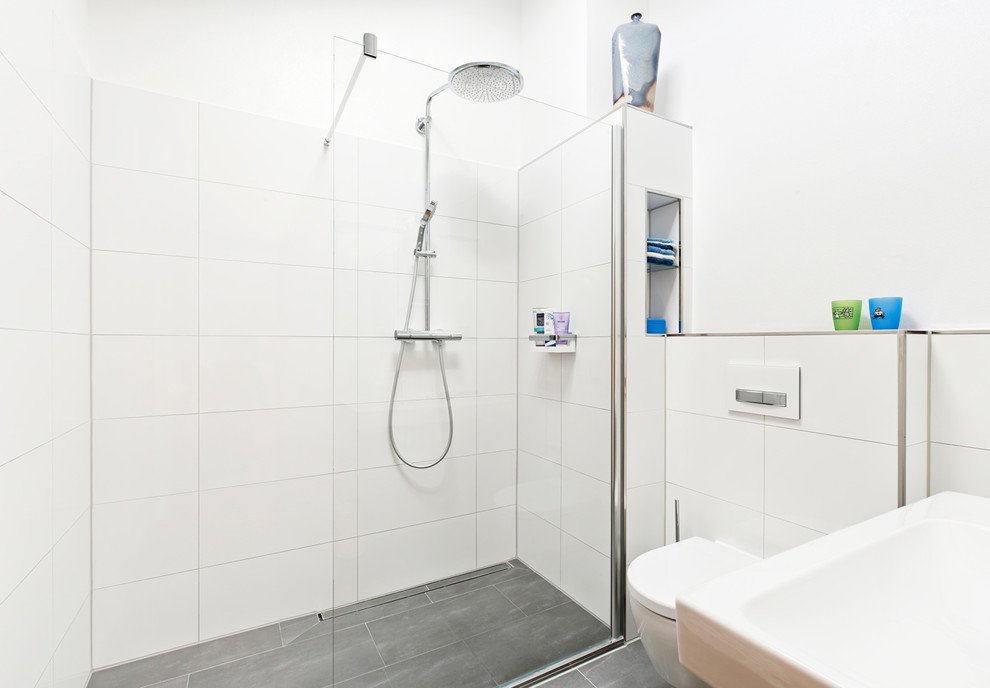 Nordisches Badezimmer mit bodengleicher Dusche und grauen Fliesen in Köln