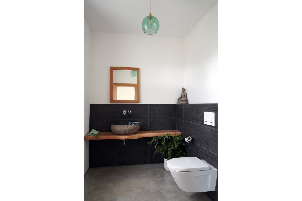 Стильный дизайн: маленькая ванная комната в современном стиле с плоскими фасадами, белыми фасадами, душем без бортиков, раздельным унитазом, черной плиткой, плиткой из сланца, белыми стенами, бетонным полом, душевой кабиной, настольной раковиной, серым полом и коричневой столешницей для на участке и в саду - последний тренд