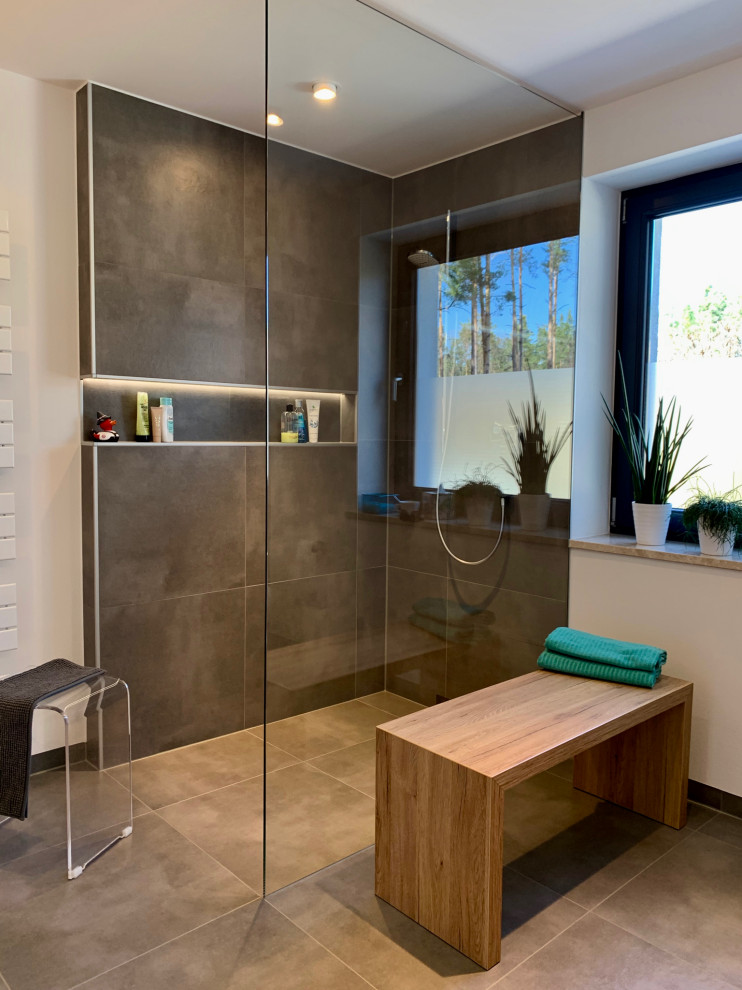 This is an example of a small contemporary shower room bathroom in Nuremberg with medium wood cabinets, grey tiles, white walls, a vessel sink, a shower bench, double sinks, a floating vanity unit, a two-piece toilet, ceramic tiles, ceramic flooring, wooden worktops, grey floors, an open shower and a drop ceiling.
