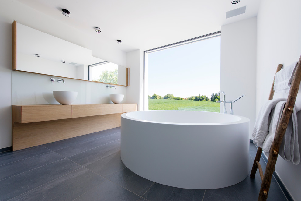 Inspiration pour une grande salle de bain principale minimaliste en bois clair avec un placard à porte plane, une baignoire indépendante, un mur blanc, une vasque, un plan de toilette en bois et un plan de toilette beige.