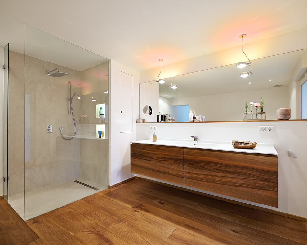 Großes Modernes Duschbad mit flächenbündigen Schrankfronten, braunen Schränken, Einbaubadewanne, offener Dusche, Wandtoilette, weißer Wandfarbe, braunem Holzboden, Einbauwaschbecken und Waschtisch aus Holz in Düsseldorf
