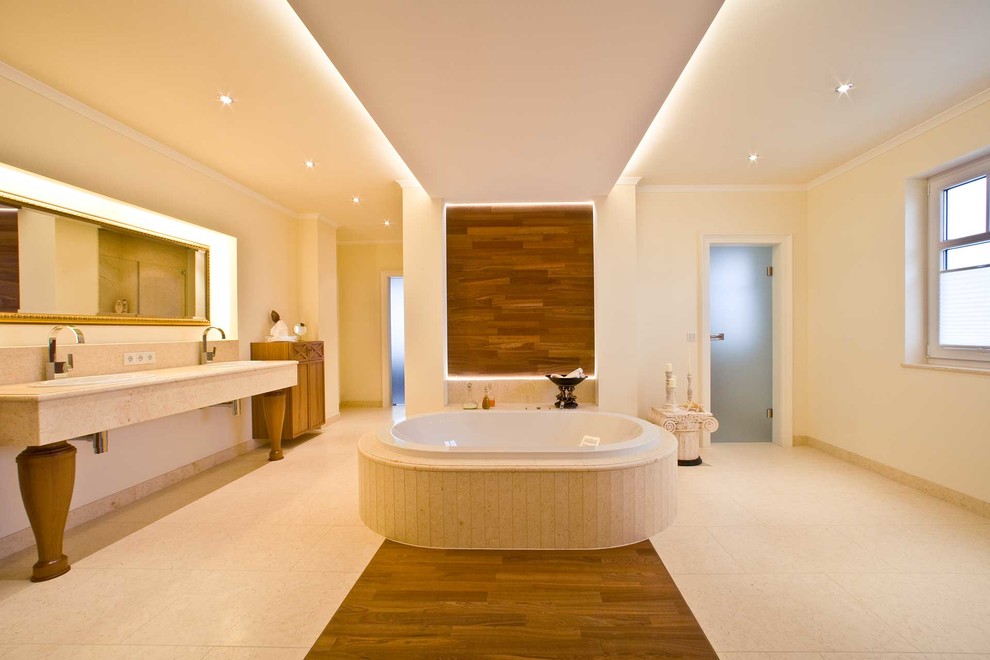 Diseño de cuarto de baño principal actual grande con bañera encastrada, paredes beige, lavabo encastrado, baldosas y/o azulejos beige y encimera de mármol